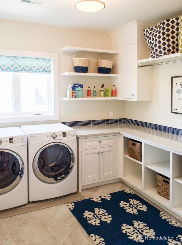 White and blue laundry room with lots of shelf storage. Fabulous Laundry room design ideas from @Remodelaholic